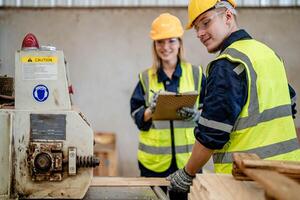 Arbeiter Tischler Arbeiten im Maschinen zu Schnitt Holz Holz. Mann und Frau sind basteln mit Holz im ein Werkstatt. zwei Handwerker oder Handwerker Arbeiten mit Zimmermann Werkzeuge oder elektrisch Maschinen. foto