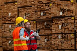 Arbeitskräfte Zimmermann tragen Sicherheit Uniform und schwer Hut Arbeiten und Überprüfung das Qualität von hölzern Produkte beim Werkstatt Herstellung. Mann und Frau Arbeitskräfte Holz im dunkel Warenhaus Industrie. foto