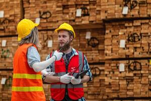 Arbeitskräfte Zimmermann tragen Sicherheit Uniform und schwer Hut Arbeiten und Überprüfung das Qualität von hölzern Produkte beim Werkstatt Herstellung. Mann und Frau Arbeitskräfte Holz im dunkel Warenhaus Industrie. foto