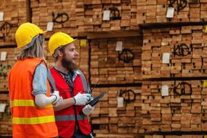 Arbeitskräfte Zimmermann tragen Sicherheit Uniform und schwer Hut Arbeiten und Überprüfung das Qualität von hölzern Produkte beim Werkstatt Herstellung. Mann und Frau Arbeitskräfte Holz im dunkel Warenhaus Industrie. foto