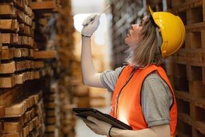 Frau Arbeiter Zimmermann tragen Sicherheit Uniform und schwer Hut Arbeiten und Überprüfung das Qualität von hölzern Produkte beim Werkstatt Herstellung. Mann und Frau Arbeitskräfte Holz im dunkel Warenhaus Industrie. foto