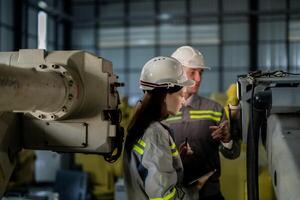 Ingenieure prüfen Steuerung schwer Maschine Roboter Arm. vielfältig Mannschaft von industriell Robotik Ingenieure versammelt um Maschine. Fachmann Maschinen Betreiber Reparatur elektrisch Roboter auf hell Digital Tafel. foto