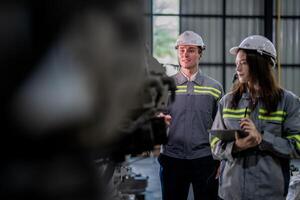 Fabrik Ingenieur Frau inspizieren auf Maschine mit Clever Tablette. Arbeiter funktioniert beim Maschine Roboter Arm. das Schweißen Maschine mit ein Fernbedienung System im ein industriell Fabrik. künstlich Intelligenz Konzept. foto