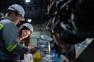 Fabrik Ingenieur Frau inspizieren auf Maschine mit Clever Tablette. Arbeiter funktioniert beim Maschine Roboter Arm. das Schweißen Maschine mit ein Fernbedienung System im ein industriell Fabrik. künstlich Intelligenz Konzept. foto