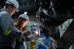 Ingenieure prüfen Steuerung schwer Maschine Roboter Arm. vielfältig Mannschaft von industriell Robotik Ingenieure versammelt um Maschine. Fachmann Maschinen Betreiber Reparatur elektrisch Roboter auf hell Digital Tafel. foto