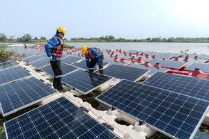 männlich Arbeitskräfte Reparatur schwebend Solar- Paneele auf Wasser See. Ingenieure konstruieren auf Seite? ˅ schwebend Solar- Paneele beim Sonne Licht. sauber Energie zum Zukunft Leben. industriell verlängerbar Energie von Grün Leistung. foto