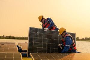 männlich Arbeitskräfte Reparatur schwebend Solar- Paneele auf Wasser See. Ingenieure konstruieren auf Seite? ˅ schwebend Solar- Paneele beim Sonne Licht. sauber Energie zum Zukunft Leben. industriell verlängerbar Energie von Grün Leistung. foto