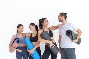 Gruppe von glücklich sportlich Frauen und Kerl tragen Körper stilvoll Sportbekleidung halten persönlich Teppiche beugte sich vor auf ein Weiß Hintergrund. warten zum Yoga Klasse oder Körper Gewicht Klasse. gesund Lebensstil und Wellness foto