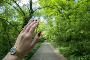 weiblich Hand mit rot Maniküre Punkte Sommer- Weg. foto