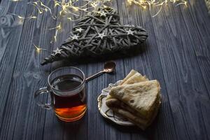 ein Tasse von Tee und Kuchen auf ein rustikal Tisch. gemütlich Winter Zeit. foto