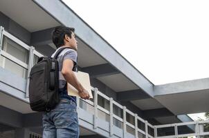 ein Schüler mit ein Rucksack halten dokumentieren und suchen gegenüber Schule foto