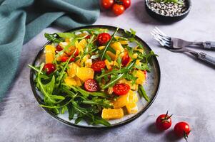 Diät Salat von Orange Scheiben, Kirsche Tomaten und Rucola auf ein Teller auf das Tabelle foto