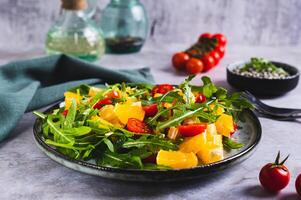 hausgemacht Salat von orange, Kirsche Tomaten und Rucola auf ein Teller auf das Tabelle foto