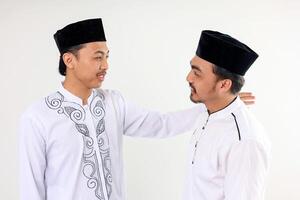 zwei asiatisch Muslim männlich Menschen Umarmung jeder und verzeihen jeder andere feiern eid al fitr foto