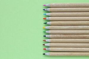 multi farbig Bleistifte isoliert auf Grün Hintergrund. zurück zu Schule Konzept. Skizzierung und Zeichnung Hobby. Schreibwaren liefern speichern. Bildung Verfahren. oben Sicht. minimal Stil Komposition foto