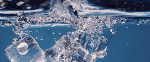 Wasser planschen und Eis Würfel. Eis planschen in ein Glas von Wasser. unter Wasser Gießen Eis Würfel fallen in klar Bewässerung Hintergrund. erfrischend Ausruhen Trinken. Eis im ein Glas mit Blau Hintergrund foto