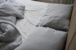 zerknittert Bett mit Kissen, Decke und zerknittert Blätter im Schlafzimmer foto