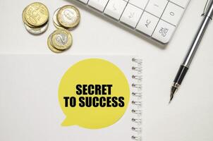 Geheimnis zu Erfolg Botschaft im Rede Blase mit Münzen, Taschenrechner, und Stift auf Weiß Hintergrund foto