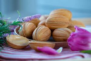 Kekse mit kondensiert Milch und lila Blumen auf ein hölzern Tabelle foto