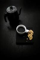 Tasse von Kaffee und Kekse auf schwarz Tisch. getönt. foto