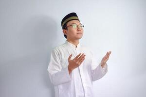 asiatisch Muslim Mann tragen Brille und Weiß Stoff tun beten Hand Pose zum Ramadhan und eid al fitr. isoliert Weiß Hintergrund foto