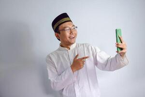 asiatisch Muslim Mann tragen Brille und Weiß Stoff zeigen Telefon Pose zum Ramadhan und eid al fitr. isoliert Weiß Hintergrund foto