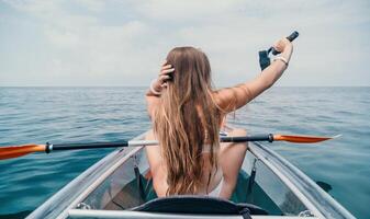 Frau im Kajak zurück Sicht. glücklich jung Frau mit lange Haar schwebend im transparent Kajak auf das Kristall klar Meer. Sommer- Urlaub Ferien und heiter weiblich Menschen entspannend haben Spaß auf das Boot foto