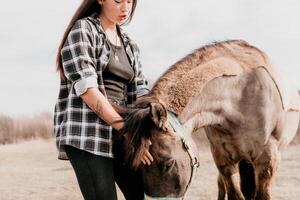 jung glücklich Frau mit ihr Pony Pferd im Abend Sonnenuntergang Licht. draussen Fotografie mit Mode Modell- Mädchen. Lebensstil Stimmung. Konzept von draussen Reiten, Sport und Erholung. foto