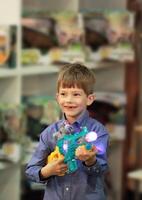 glücklich aufgeregt Junge im ein Abteilung Geschäft Einkaufen Einkaufszentrum testen ein Spielzeug Gewehr und wählen ein Weihnachten gegenwärtig. schwarz Freitag Einkaufen. verschwommen Hintergrund foto