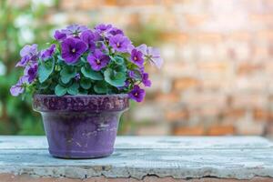 ai generiert violett Blume Topf auf Tabelle auf Backstein Mauer Hintergrund im Garten. foto