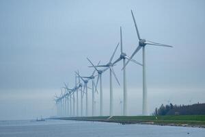 Wind Turbinen im ein Reihe auf das Küste im das Nebel und Nebel foto