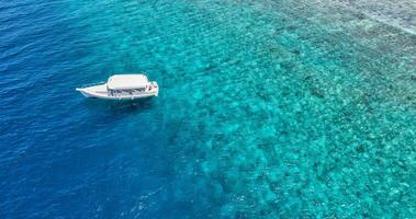 Strand und Kristall klar Lagune mit Weiß Boot. Türkis Wasser Hintergrund oben Sicht. Sommer- Seelandschaft von Luft. oben Aussicht von Drohne. Sommer- Ferien und Reise im Luxus exotisch Ziel. Paradies foto