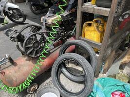 Auto Reparatur Geschäft, Luft Pumpe Maschine Kompressor, Stapel von benutzt Öl Flaschen und benutzt Reifen foto