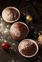 Schokolade Muffins mit pulverisiert Zucker auf oben auf ein schwarz Hintergrund. Weihnachten Dekoration . immer noch Leben schließen hoch. Essen Foto. foto