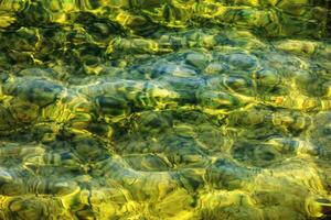 Hintergrund von das Wasser von See traunsee im das Küsten Bereich. bunt Textur von Steine unter Wasser. foto