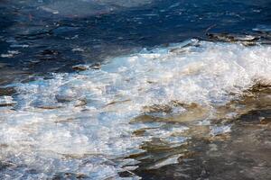 eisige Flussoberfläche. Textur von Eis mit Schnee bedeckt. Winterhintergrund. foto