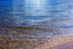 Hintergrund von das Wasser von See traunsee im das Küsten Bereich. bunt Textur von Steine unter Wasser. foto