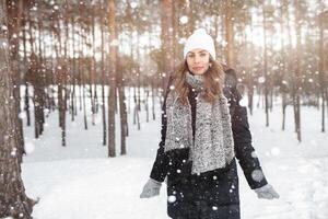 schönes Winterporträt der jungen Frau in der schneebedeckten Winterlandschaft foto