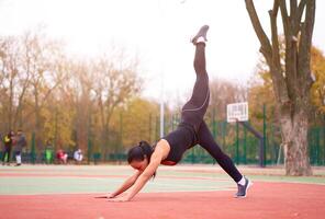 glücklich Mädchen tun Fitness Übungen draussen auf Spielplatz. gesund Lebensstil. Morgen trainieren positiv Emotion lächelnd sportlich Menschen foto