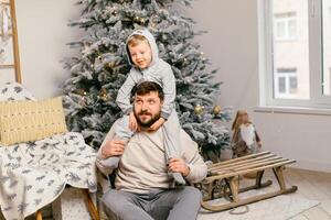 Urlaub Weihnachten gut aussehend Vater spielen mit klein süß Sohn in der Nähe von dekoriert Neu Jahr Baum beim Zuhause foto