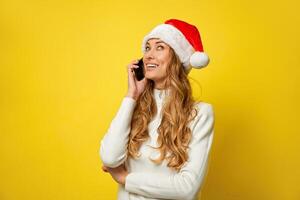 Frau Weihnachten Santa Hut Gelb Studio Hintergrund mit Smartphone im Hand foto