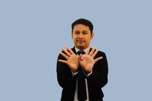 Erwachsene asiatisch Mann lächelnd beim das Kamera und tun Taube Finger Zeichen foto