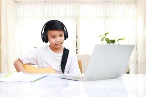 asiatisch Junge tragen schwarz Kopfhörer lernen Musik- online beim heim. Konzept von online Bildung durch das Internet. modern Lernen foto