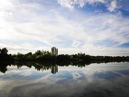 See mit Blau Himmel und Wolken reflektieren im still Fluss foto