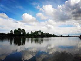 See mit Blau Himmel und Wolken reflektieren im still Fluss foto