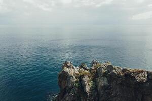 Scharf Klippen hängen Über das Ozean, dramatisch Marine Hintergrund foto