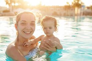 Mama und wenig Tochter sind gespielt im das öffnen Schwimmen Schwimmbad. Familie mit einer Kind auf Ferien im warm Länder. positiv Menschen auf Urlaub. foto