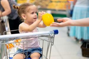 wenig kaukasisch Mädchen wählt frisch Gemüse im das Supermarkt. foto