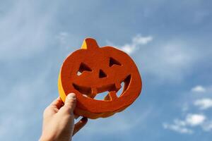 Halloween geschnitzt Kürbis im das Mann Hand auf das Wolke Himmel Hintergrund foto