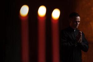 Porträt von gut aussehend katholisch Priester oder Pastor mit Hund Kragen, dunkel rot Hintergrund. foto